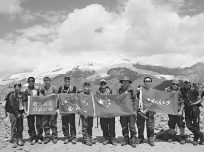 登山队在峰顶合影，背后是厄尔布鲁士峰。